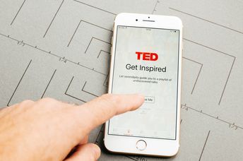 Male hand holding New Apple iPhone 7 Plus after unboxing and testing by installing the app application software TED speaking media app