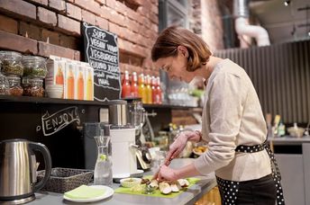 happy woman or barmaid cooking at vegan cafe