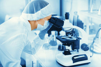 Young woman medical researcher looking through microscop slide in the life science