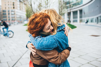 Two friends meeting in the street of the city and hugging