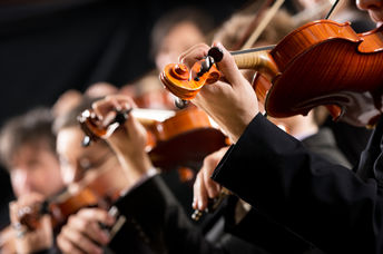 Symphony orchestra first violin section performing on dark background