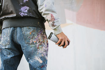 Graffiti artist with aerosol spray bottle near the wall