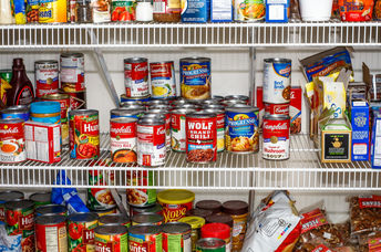 A model of the Free Little Pantry stands fully stocked by the side of the road.