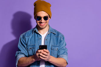 Smiling man on cellphone creates positivity using social media.