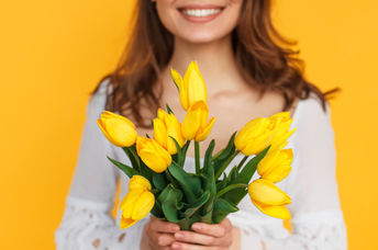 Photo of happy woman holding flowers to illustrate kindness