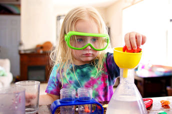A little girl playing with a science toy.
