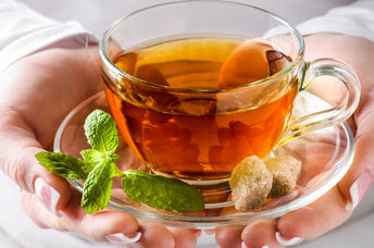 A woman holding a cup of headache soothing tea.
