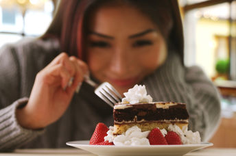 A woman happily indulges in a fancy dessert.