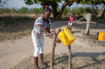 Girl washing her hands with a tippy tap.