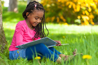 Young girl reading a book outside.