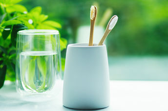 Bamboo toothbrushes in a cup and glass with water