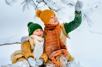 Two young girls happily play in the snow.