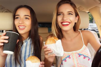Young women eating fast food in a car.