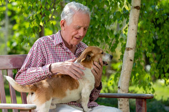 Senior man cuddling a dog outside.