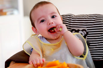 Cute baby eating cooked vegetables.