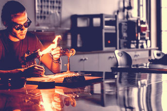 Glassblowing professional working on a torch flame with glass tubes.