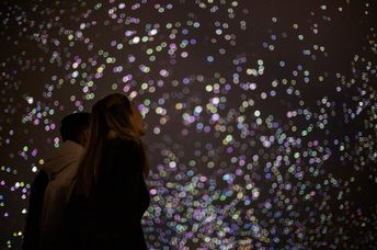 A woman watches silent, organic fireworks in the sky.