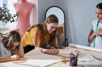 Cute girls drafting sewing patterns for dressmaking.