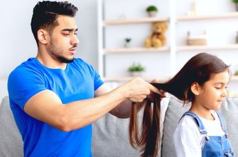 A young father making a braid for his little daughter.