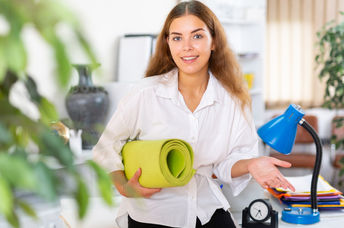 Happy young office worker with yoga mat.