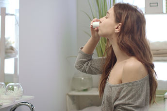 A woman using a mouthwash.