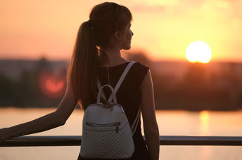 A young woman standing by the lake.