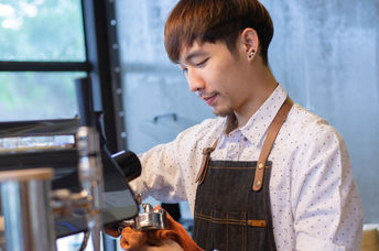 Barista at work cleaning equipment in a café.