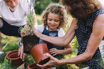 Happy kid and her grandparents working in the garden.