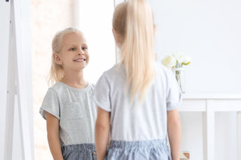 A little girl looking in the mirror.