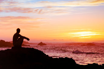 A woman sitting by the sea.