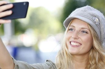 A young woman smiles as she poses for a selfie.