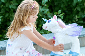 Girl playing with a unicorn plush toy.