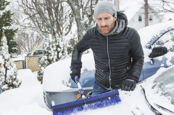Man cleaning off neighbor's snowbound car,