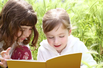 Two girls reading a book they found in a park.