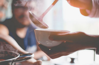 A woman warms up with a hearty soup.
