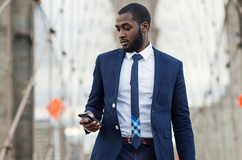 Young businessman using mobile phone on Brooklyn Bridge, New York City.