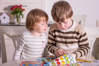 Two kids playing with stickers.