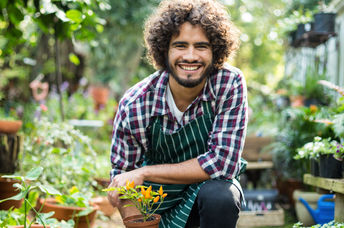 A smiling gardener with a plant.