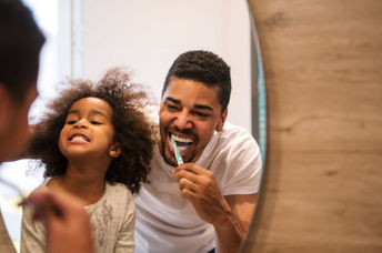 A woman looks in the mirror as she brushes her teeth.