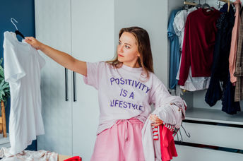 Woman cleaning out unwanted clothing from her closet.