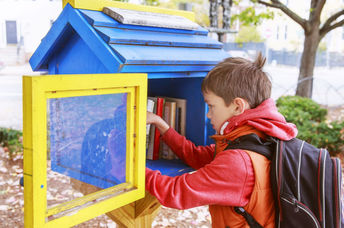 Child taking a book from a little street library.