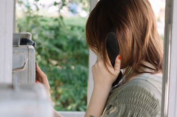 Young woman talking on a phone surrounded by flowers.