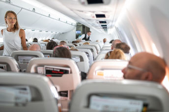 Young woman aboard an airplane walking in the aisle