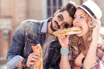Couple enjoying a sandwich lunch outside.