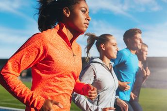 Young woman running with her team in a stadium.