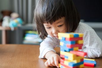 Little preschooler playing with wooden blocks.