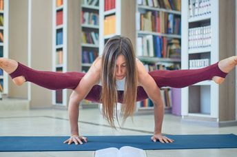 Young woman reading and practicing yoga in the library.