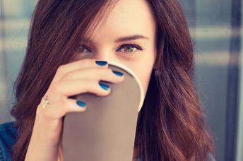 Smiling woman drinking coffee from a paper cup.