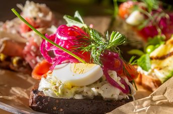 A traditional Danish sandwich with salmon, egg, and salad on rye bread.