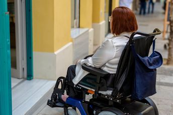 Woman cannot access a store that does not have a wheelchair ramp.